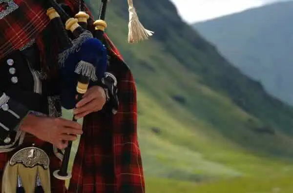 Bagpiper playing in a Highland landscape