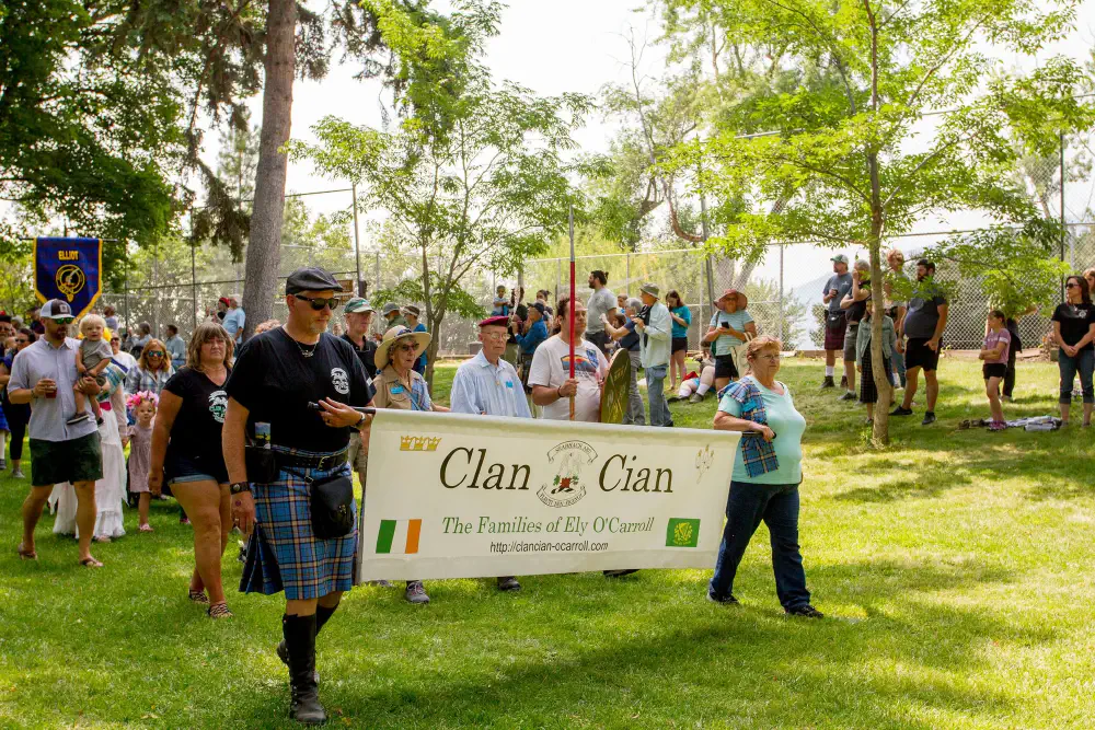 Participants carrying a Clan Cian banner during an outdoor clan procession.